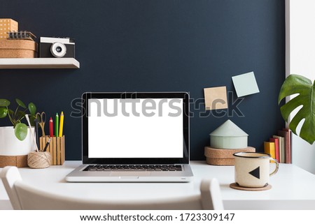 Home office with laptop mockup, supplies, cactus and books near navy blue wall. Home learning concept. Trendy, creative desk. Royalty-Free Stock Photo #1723309147