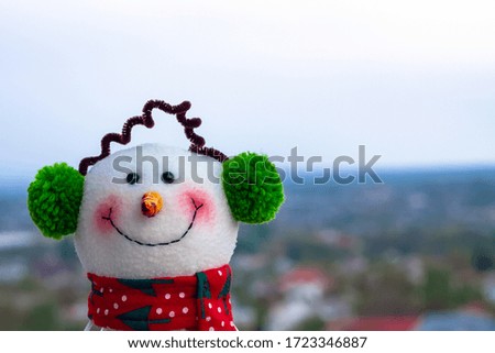 Funny snowman toy is standing upon city on the horizon 