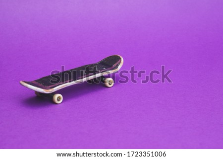 Small skateboard on purple background. tiny skate for fingers. fingerboard close up. copy space