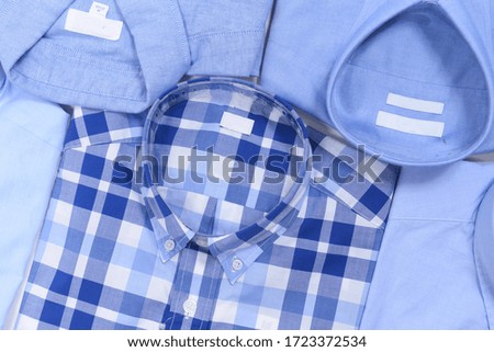 Top view folded of new blue man's shirt and plaid long sleeve shirt
