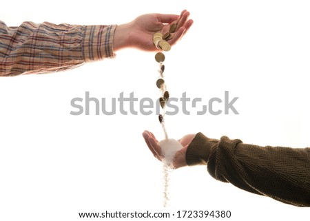 One hand giving money to another that as it falls turns to sand