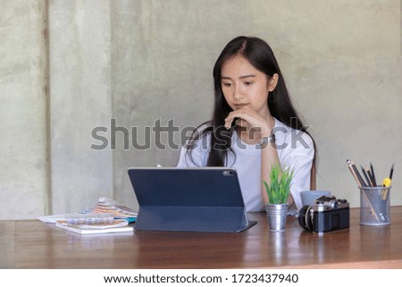 Portrait of young asian female designer or photographer working with tablet at home office, working from home concept.