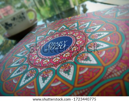relaxing with my diary for the year 2020 with mandala art cover with my cup of coffee and nature as Bokeh background in kanyakumari
