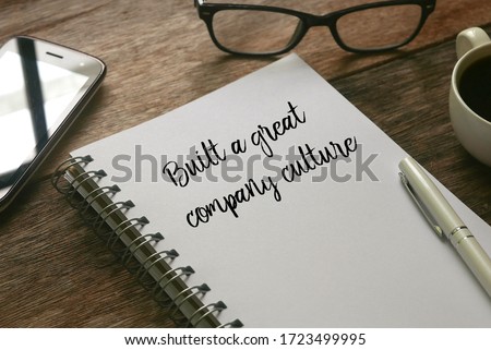 Selective focus of mobile phone,glasses,a cup of coffee,pen and notebook written with ' Built a great company culture ' on wooden background. Royalty-Free Stock Photo #1723499995