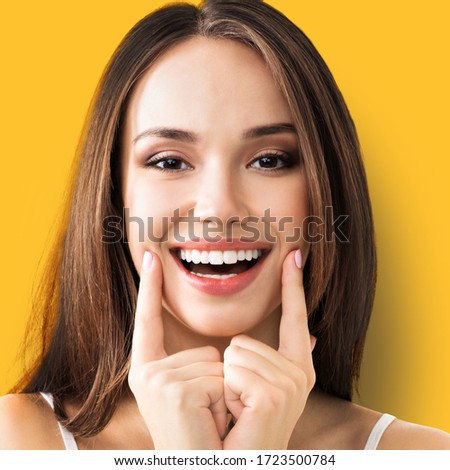 Face portrait of young woman showing smile, in casual smart clothing, standing over yellow color background. Caucasian model - optimistic, positive, happy feeling concept. Square composition.
