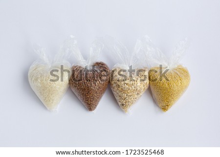 various groats in small plastic bags on a white background. Rice and oatmeal, buckwheat and millet
