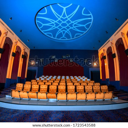 Large cinema theater interior with seat rows for audience to sit in movie theater premiere by cinematograph projector. The cinema theater is decorated in classical for luxury feel of movie watching. Royalty-Free Stock Photo #1723543588