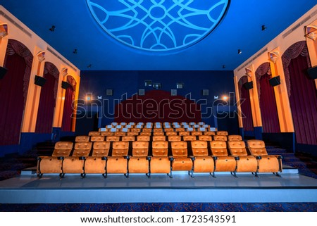 Large cinema theater interior with seat rows for audience to sit in movie theater premiere by cinematograph projector. The cinema theater is decorated in classical for luxury feel of movie watching. Royalty-Free Stock Photo #1723543591