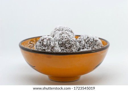 Coconut balls in a yellow bowl with white background