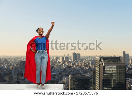 women's power and people concept - happy african american woman in red superhero cape over tokyo city skyscrapers on background
