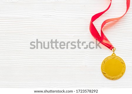 Gold medal with red ribbon - winner, success concept - on white wooden background top view copy space