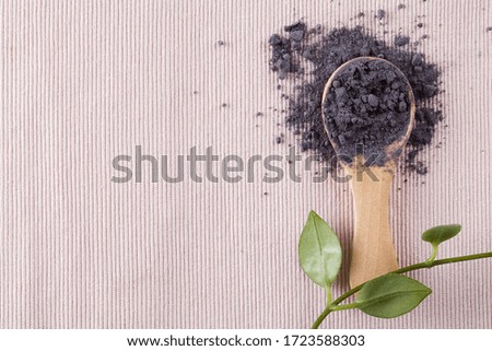 matcha blue tea powder in wood spoon on pink background with green leaves. top view copy space healthy food concept