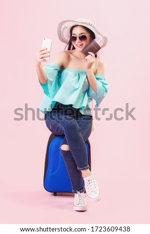 Asian pretty young girl smiling wear sunglasses and take a selfie by smartphone, Young women backpacker take a selfie and holding passport in studio pink background. Travel in amazing thailand.