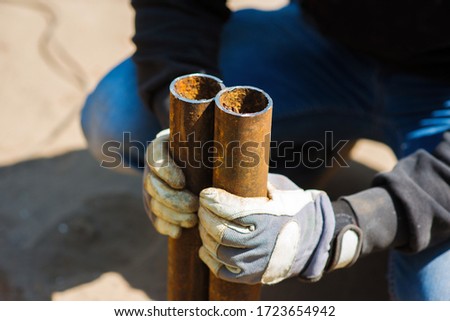 A worker holds in his hands two pieces of a metal pipe cut off