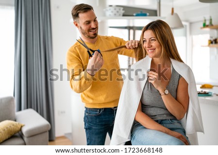 Couple having hair cut at home during quarantine coronavirus pandemic, online hairdressing on tablet Royalty-Free Stock Photo #1723668148
