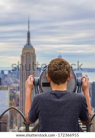 Young boy looking at Manhattan skyline with a binocular