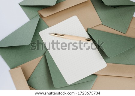 Composition with craft and olive envelopes, a white blank sheet and pen. Blank sheet for inscription