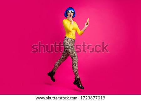 Full body profile photo of crazy funny lady jump high walk street browsing telephone wear specs yellow turtleneck blue bob wig boots leopard pants isolated bright pink color background
