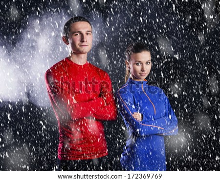 Young fitness athletes are posing in studio with black dusty background.