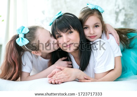Daughters hug and kiss their beloved mother.