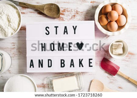Stay home and bake covid 19 conceptual image for coronavirus pandemia,  with a lightbox texting stay home and bake,circled by tools and ingredients for baking bread and cake during quarantine,top view