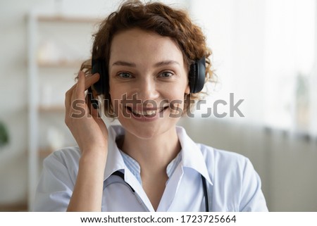 Smiling female doctor wearing headset looking at camera. Remote online medical chat consultation, telemedicine distance services, virtual physician conference call concept. Head shot close up portrait Royalty-Free Stock Photo #1723725664