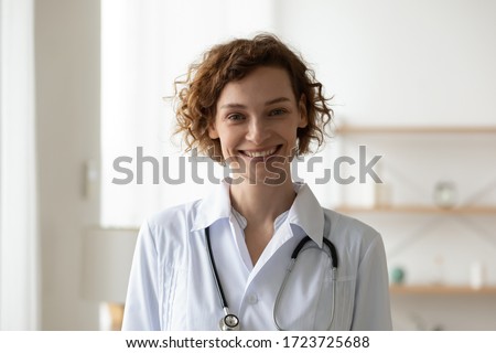 Smiling young adult woman doctor wearing white medical coat and stethoscope head shot close up portrait. Happy female physician, therapist, general practitioner looking at camera standing in hospital. Royalty-Free Stock Photo #1723725688