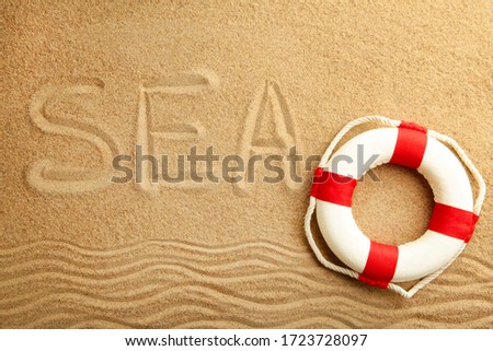 Inscription sea with lifebuoy on the sea sand. Top view