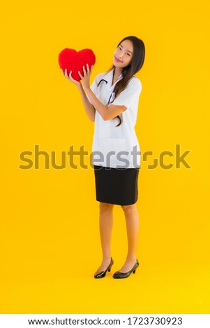 Portrait beautiful young asian doctor woman show heart for symbol of love on yellow isolated background