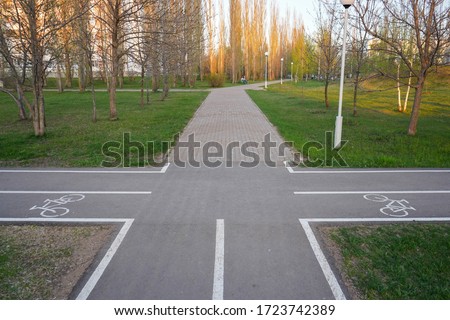 Two intersecting bike paths in the Park. Bike path sign on asphalt