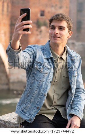 happy man taking a selfie in a European city, brick, castle