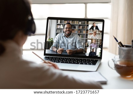 Back view of female employee have webcam conference on computer with multiracial colleagues, woman talk brainstorm on video call with diverse coworkers, engaged in web team online briefing from home Royalty-Free Stock Photo #1723771657