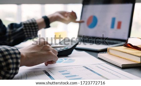 Close up, Businesswoman analyzing financial data on document and laptop computer screen