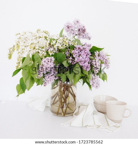 Lilac bouquet on a white table. Scandinavian minimalism. Flowers in the kitchen. Bouquet of lilac with utensils