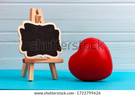 decorative easel and red heart on a blue, wooden background, place for text