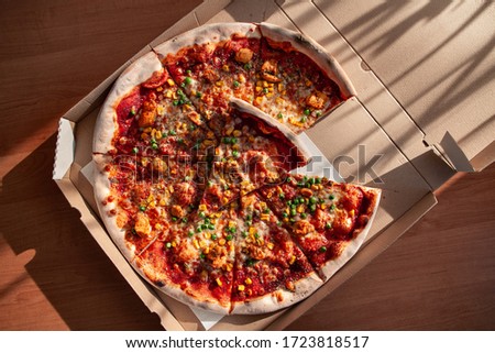 Top view of hot tasty pizza ready to eat. Pizza in a cardboard box against a sunny background. Pizza delivery. Pizza menu.