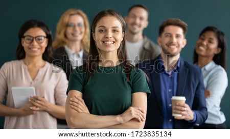 Close up headshot portrait of happy businesswoman hands crossed posture. Different age and ethnicity businesspeople standing behind of female company chief business. Leader of multi-ethnic team