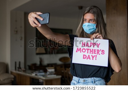 Blonde girl wearing a mask is taking a selfie for mother's day during COVID-19. Royalty-Free Stock Photo #1723855522