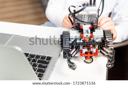 Social distancing & Online learning concept, Teenager assemble and program his robot school project at home through video lessons with his computer laptop during school closed due to Covid-19 pandemic Royalty-Free Stock Photo #1723871536
