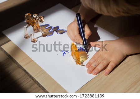 child enthusiastically outlines the contour with felt-tip pen in contrasting shadows from small toy figures of  camel and  hedgehog. drawing of preschooler, ideas for  development of creative thinking