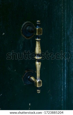 An old wooden door with an elegant rectangular metal handle.                               