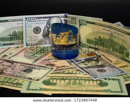 Figure of an oil derrick with a drop of oil close-up on a background of dollars