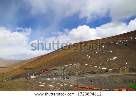 Plateau winding road, blue sky and white clouds, snowy mountains in the distance, the text in the picture means: Montara Pass, 5363 meters above sea level