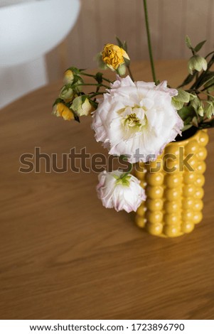 Bouquet in a yellow ceramic designer vase. It's on the table .