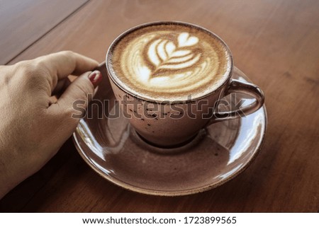 A cup of coffee with latte art on top on wooden table, closeup