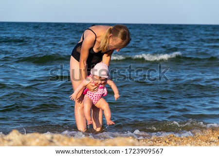 Caucasian female baby first time at sea, jump into water and have fun