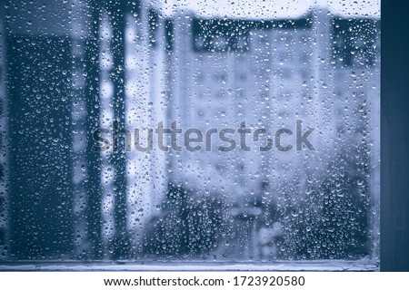 rainy droplets on a blue window glass transparent surface. drops on window shield in a rainy days  in night city. stormy weather. isolation sad depression concept.  rainy season. stay home.