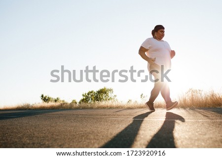 Overweight woman on morning run on the road. Plus size female exercising in morning. Royalty-Free Stock Photo #1723920916
