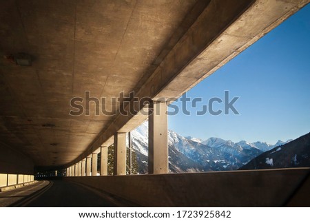 A long road tunnel opens to the surface with mountain views. The concept of reducing travel time.