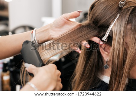 hair stylist creates volume and styling for brown hair on a woman's head in a beauty salon Royalty-Free Stock Photo #1723944622